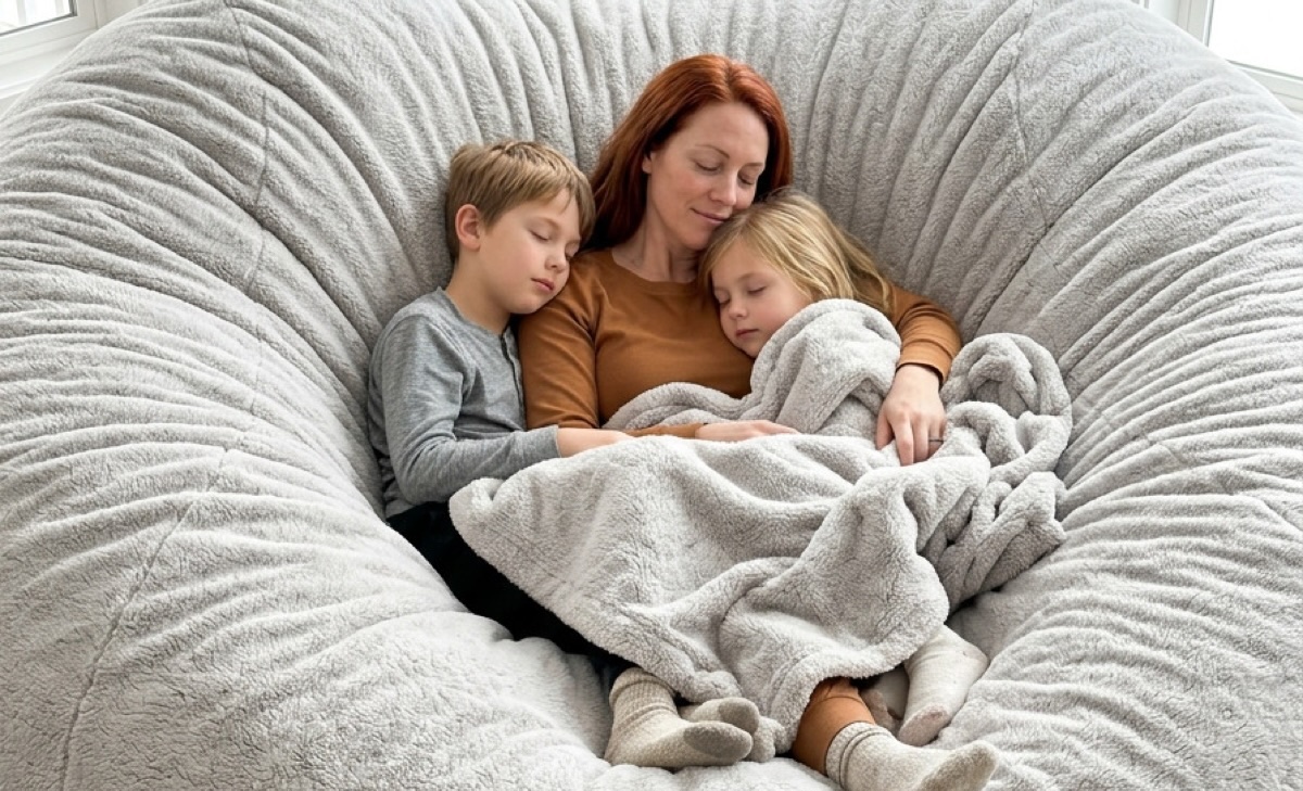 A mother and her two children asleep together on the 7ft ash Cosac beanbag in a warm family living room